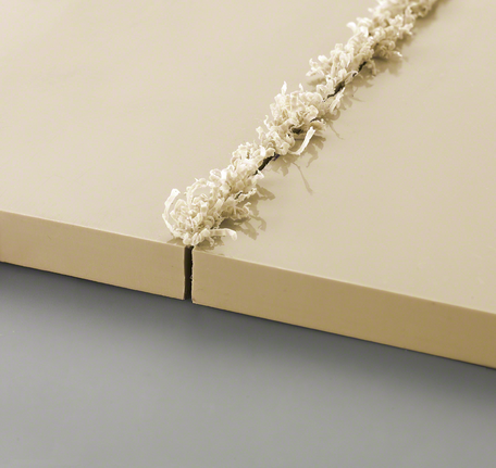 Two beige panels with a fresh groove cut and curled shavings along the edge.