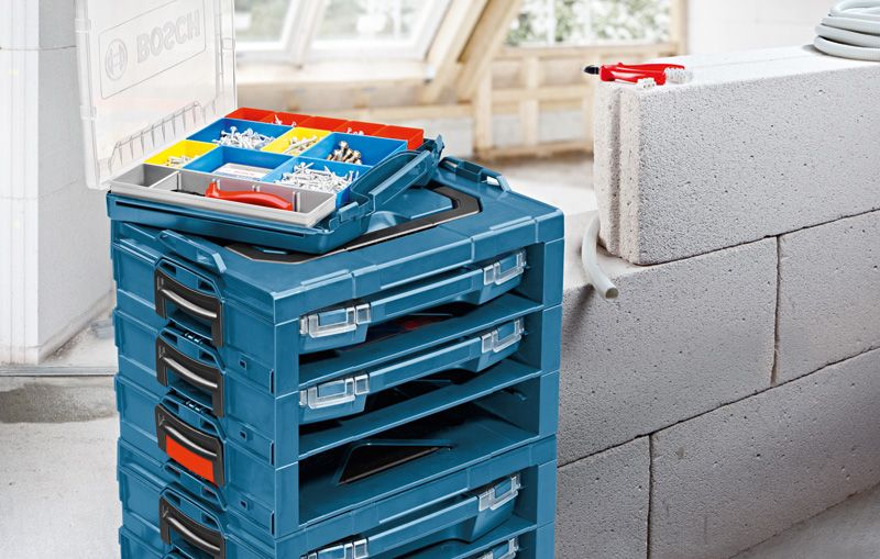 Stacked blue toolboxes with an open organizer tray holding screws and wall plugs nearby.