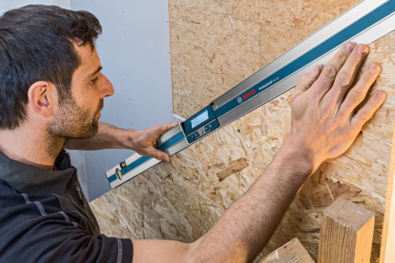 GIM 120 Person using a digital inclinometer to measure the angle of a wooden surface.