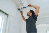A person measures the angle between a wall and ceiling using an angle measurer.
