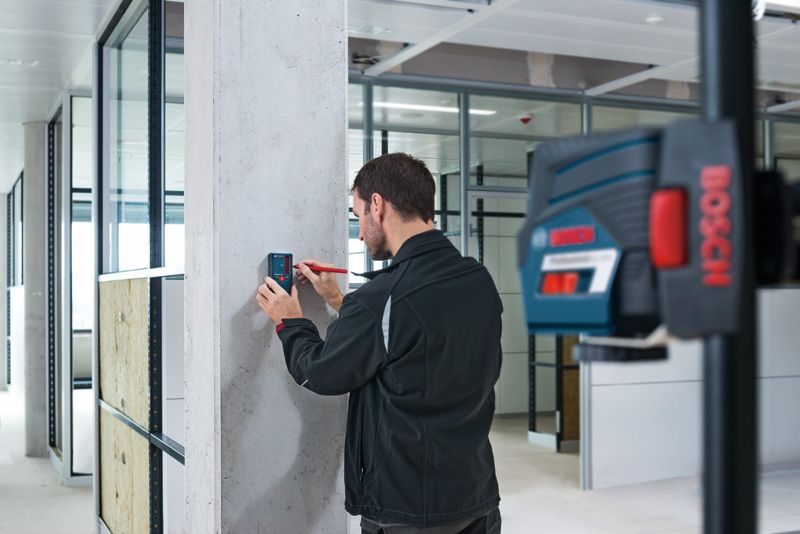 LR 6 A person aligns a laser receiver on a concrete pillar in a modern office.