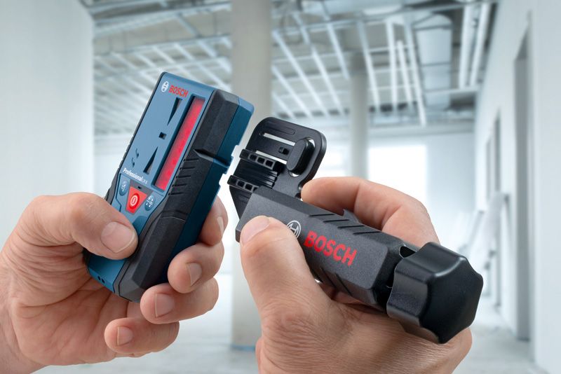 LR 6 A person assembles a laser measure and bracket in a building under construction.