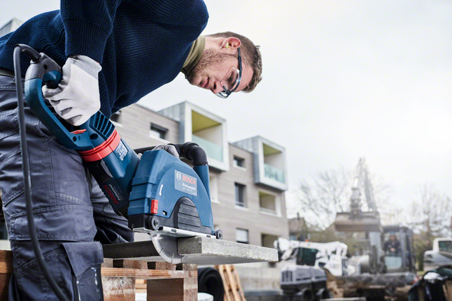 Standard for Concrete diamond cutting disc Person wearing safety equipment uses a power saw to cut a concrete slab outdoors.