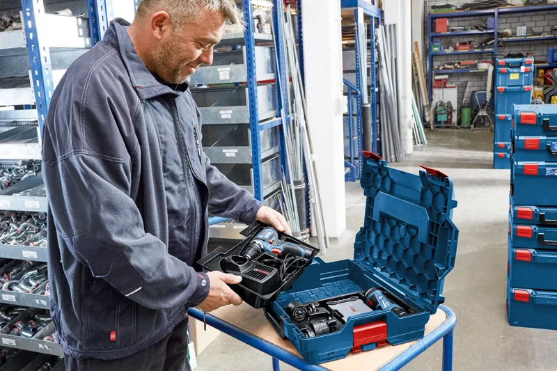 L-BOXX 102 A person in a workshop unpacks a cordless tool set from a hard plastic case.