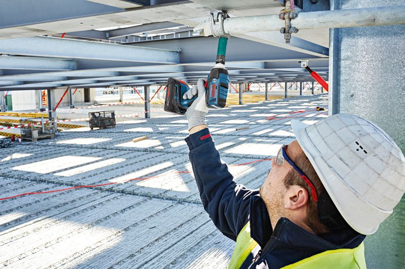 ProCORE18V 4.0Ah A person wearing safety equipment uses a cordless impact wrench on a metal beam.