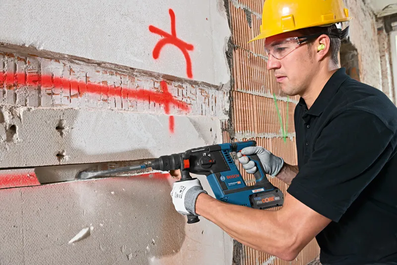 ProCORE18V 8.0Ah A person wearing safety equipment chisels a groove into a marked concrete wall.