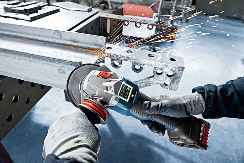 ProCORE18V 8.0Ah A person wearing safety equipment grinds metal, producing sparks with a cordless angle grinder.