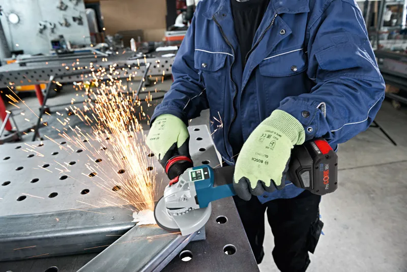 ProCORE18V 8.0Ah A person wearing safety equipment grinds metal with an angle grinder, producing sparks.