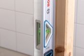 Laser leveling tool checking vertical alignment of a wooden beam.