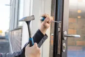 Person using a hammer and screwdriver to install a door lock mechanism.