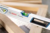 Aluminum optical level measuring the alignment of wooden beams.