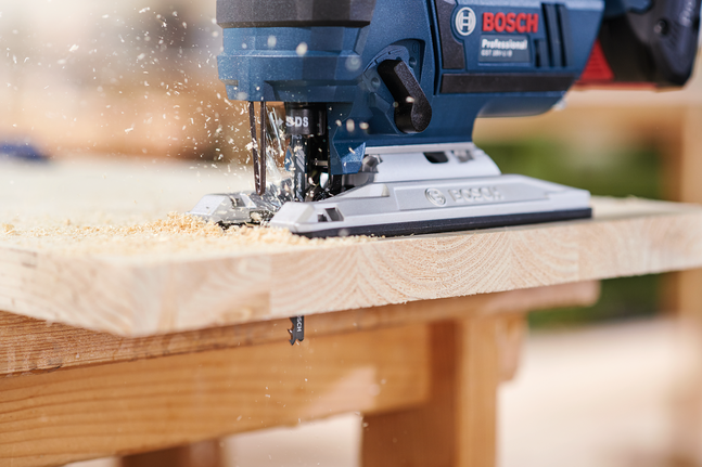 Jigsaw blade T 144 D Jigsaw cutting through a wooden plank with sawdust flying.
