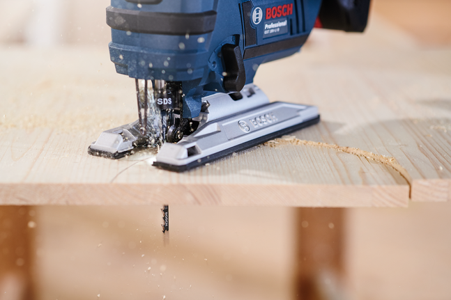 Jigsaw blade T 144 D Jigsaw cutting a curved line in a wooden board, sawdust flying.