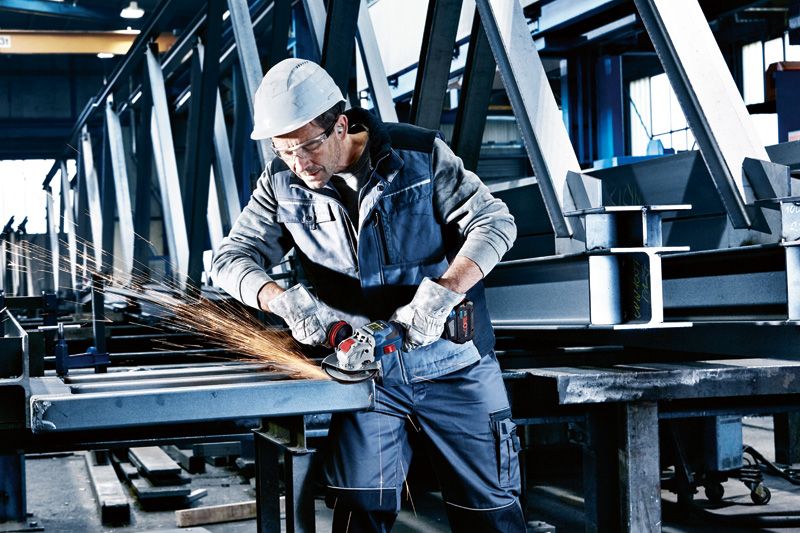 GWX 18V-15 SC A person wearing safety equipment grinds metal beams with a cordless angle grinder.