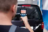 Person uses a thermo camera to scan the rear window of a vehicle.