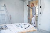 A person uses a laser measure to check wall distance at a construction site.