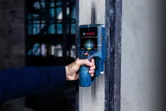 Person scanning a wall using a detector for hidden objects.