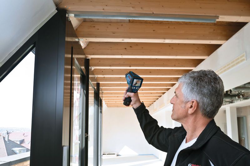 GIS 1000 C A person scans ceiling beams with a handheld inspection device.