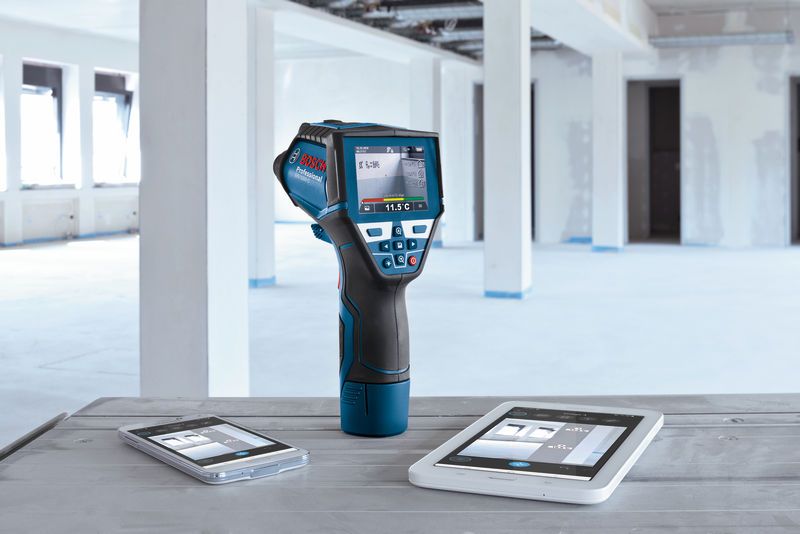 GIS 1000 C Digital thermal scanner displaying temperature data, placed between two smart devices on a worktable.