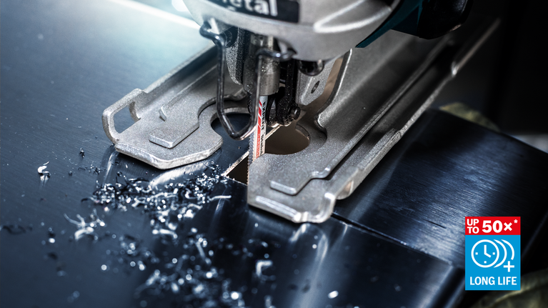 Jigsaw blade cutting through a metal sheet with metal shavings on the surface.
