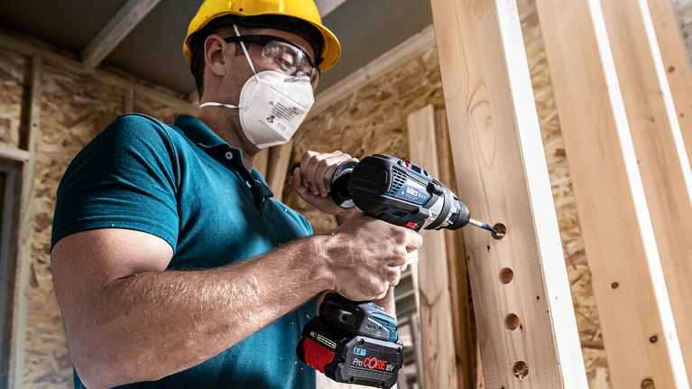EXPERT Self Cut Speed Spade Drill Bit 40 x 152 mm Person wearing safety equipment drills holes in wooden beams.