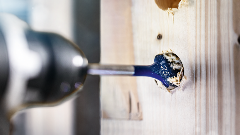 EXPERT Self Cut Speed Spade Drill Bit 40 x 152 mm Flat drill bit making a hole in a wooden board.