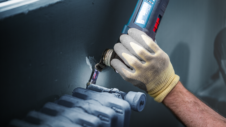 EXPERT MetalMax AIZ 32 AIT Multitool Blade 40 x 32 mm Person wearing safety equipment uses a power tool to cut around a pipe near a radiator.