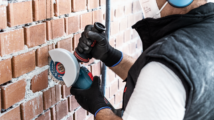 Object #200360656: 2793282_web_004 Person wearing safety equipment cuts into a brick wall with a power tool.