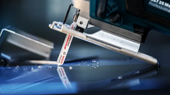 Jigsaw with a fine-toothed blade cutting through a clear glass sheet.