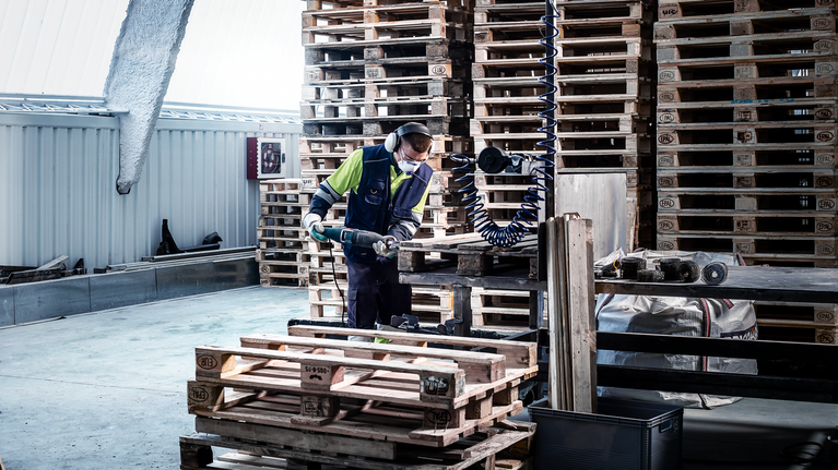 EXPERT Hard Nail Pallets S1122CHM Reciprocating Saw Blade 10-pc A person wearing safety equipment uses a power tool to cut wood pallets.