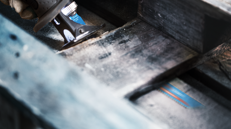 EXPERT Hard Nail Pallets S1122CHM Reciprocating Saw Blade 10-pc Person using a reciprocating saw to cut through a wooden beam.