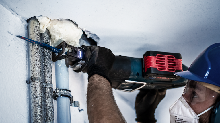 EXPERT ‘Multi Material’ S 1156 XHM Reciprocating Saw Blade 1-pc A person wearing safety equipment cuts through metal pipes using a reciprocating saw.