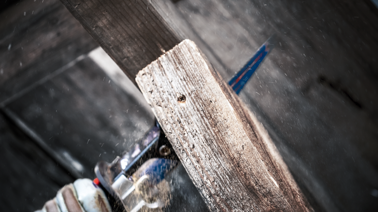 EXPERT ‘Multi Material’ S 1156 XHM Reciprocating Saw Blade 1-pc Person wearing safety equipment cuts a wooden plank with a reciprocating saw.