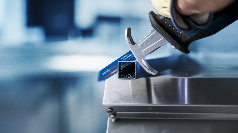 EXPERT ‘Thin Tough Metal’ S 922 EHM Reciprocating Saw Blade 1-pc Person wearing safety equipment uses a reciprocating saw to cut a metal tube.