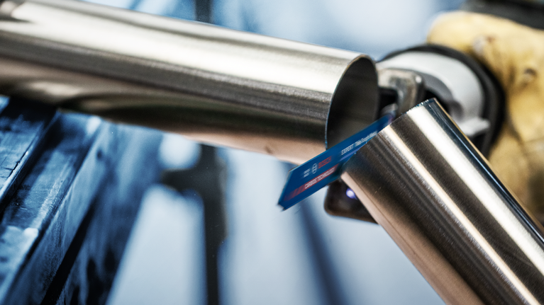 EXPERT ‘Thin Tough Metal’ S 922 EHM Reciprocating Saw Blade 1-pc Person wearing safety equipment cuts a metal pipe with a reciprocating saw.