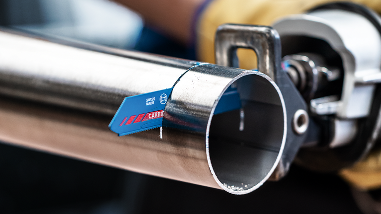 EXPERT ‘Thin Tough Metal’ S 922 EHM Reciprocating Saw Blade 1-pc Person wearing safety equipment uses a reciprocating saw to cut a metal pipe.