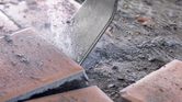 Chisel demolishing ceramic floor tiles, creating dust and debris.