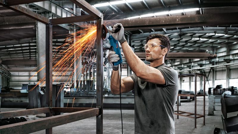 GWS 9-100 P Man grinding metal frame.