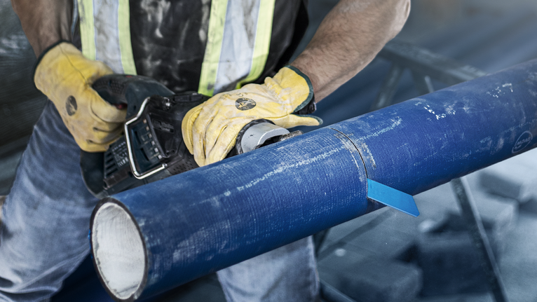 EXPERT ‘Cement Cast Iron’ S 1750 RD Reciprocating Saw Blade 1-pc Person wearing safety equipment cuts through a large blue pipe with a power tool.