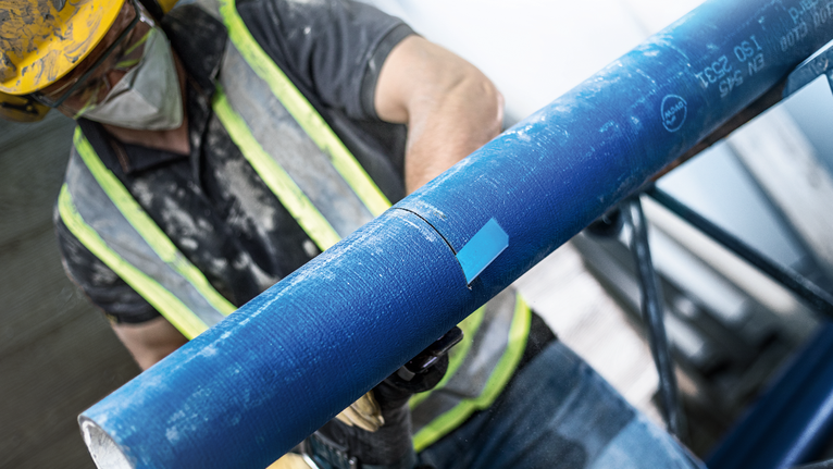 EXPERT ‘Cement Cast Iron’ S 1750 RD Reciprocating Saw Blade 1-pc Person wearing safety equipment cuts a blue pipe with a power tool.