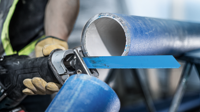EXPERT ‘Cement Cast Iron’ S 1750 RD Reciprocating Saw Blade 1-pc Person wearing safety equipment cuts a large blue pipe using a reciprocating saw.