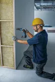 Worker installing drywall panel.
