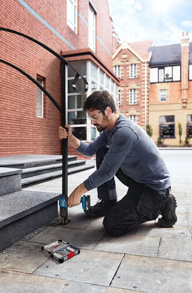 GDS 18V-350 + GSB 185 Combo A person wearing safety equipment drills into stone steps, installing a metal handrail.