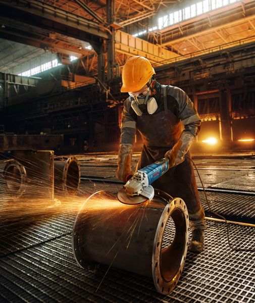 GWS 30-180 B Worker grinding metal pipe.