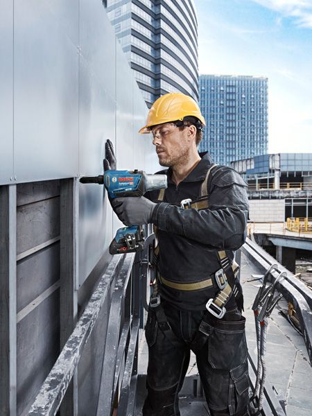 GRG 18V-16 C Person wearing safety equipment drills into a metal panel on a building exterior.