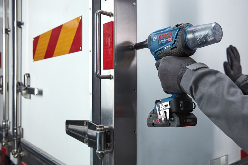 GRG 18V-16 C A person wearing safety equipment uses a cordless impact driver on a metal truck door.