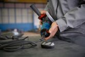 Person wearing safety equipment connects a power tool on a workbench.