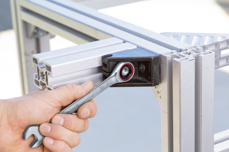 Ratchet Spanner Set 10 pc A person tightens a bolt on a metal frame with a combination wrench.