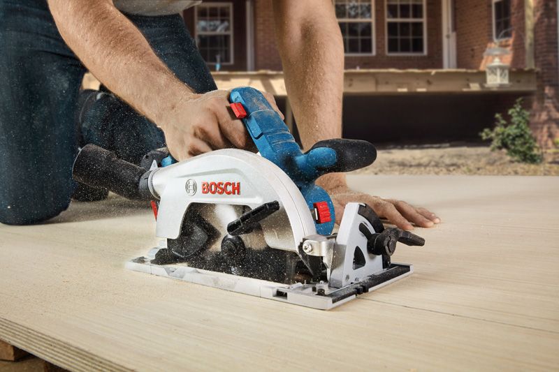A person cuts wood with a cordless circular saw outdoors.