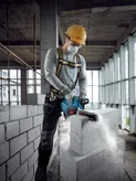 A person wearing safety equipment cuts an AAC block with a power cutter in a building under construction.